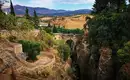 Blick auf die Tajo-Schlucht in Ronda mit Brücke und üppiger Vegetation.