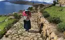 Frau auf Isla del Sol in traditioneller Kleidung Frau in traditioneller Kleidung auf steinigem Pfad bei Isla del Sol, mit Blick auf den See.