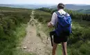 Wandern auf dem Wicklow Way in Irland Ein Wanderer auf einem Pfad im Wicklow Way mit Rucksack, umgeben von grüner Landschaft.