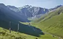 Alpenpanorama im Sommer Grüne Berglandschaft im Sommer mit schneebedeckten Gipfeln, klarer Himmel.