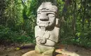 Archäologische Statue in San Agustín Steinstatue inmitten üppiger Vegetation in San Agustín, Kolumbien.