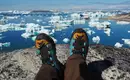 Einfach mal die Seele baumeln lassen und die Aussicht genießen Person mit Wanderstiefeln entspannt mit Blick auf Eisberge in Grönland.