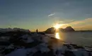 Skitour bei Sonnenuntergang - ist das ein Panorama?! Person genießt Winterlandschaft auf den Lofoten mit Meerblick im Sonnenuntergang.