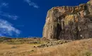 Tolle Ausblicke in den Drakensbergen Menschen wandern entlang einer steilen Felswand in den Drakensbergen, Südafrika, unter blauem Himmel.