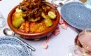 Traditionelle marokkanische Tajine Marokkanische Tajine mit Gemüse und Fleisch auf einem Tisch mit Geschirr und Weinglas.
