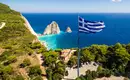 Atemberaubendes Panorama während unserer Wanderungen Griechische Flagge weht über der Küste von Zakynthos mit blauem Meer und weißen Felsen.
