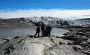 Wanderung in Grönlands arktischer Landschaft Gruppe von Wanderern vor einem Gletscher in Grönland mit felsigem Gelände und blauem Himmel.