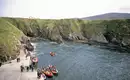 Küste von Arranmore Island Boote und Menschen an der felsigen Küste von Arranmore Island, Irland.