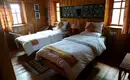 Eine unserer gemütlichen Lodges in Nepal Ein gemütliches Zimmer in einer Lodge mit zwei Betten, Holzwänden und Fenstern.
