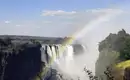Spektakuläre Victoria-Fälle mit Regenbogen Die Victoria-Fälle mit einem Regenbogen und sprühendem Wasser.