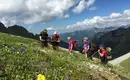 Enzian Freunde unter sich Gruppe von Wanderern in alpiner Landschaft mit blühenden Wiesen und Bergblick in den Schladminger Alpen.