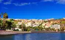 Farbige Küstenstadt auf La Gomera Bunte Gebäude vor einem blauen Himmel an der Küste von La Gomera, umgeben von Palmen.