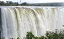 Victoriafälle in voller Pracht Blick auf die donnernden Victoriafälle in Simbabwe, umgeben von üppiger Vegetation.