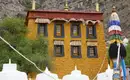Farbenfrohes Kloster in Tibet Ein gelbes tibetisches Klostergebäude mit bunten Verzierungen in einer bergigen Landschaft.
