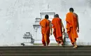 Buddhistische Mönche auf dem Weg zum Tempel Drei buddhistische Mönche in orangenen Roben gehen eine Steintreppe hinauf.