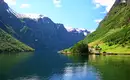 Idyllische Fjordlandschaft in Norwegen Norwegischer Fjord mit grünen Hängen und schneebedeckten Bergen unter blauem Himmel.