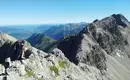 Unsere Gratetappe Wanderer auf felsigem Grat mit Alpenpanorama, blauer Himmel.
