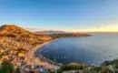 Blick auf den Titicacasee bei Sonnenuntergang Ein Panoramablick auf eine Bucht des Titicacasees mit Bergen und Booten im goldenen Sonnenuntergang.