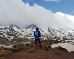 Frau mit blauem Rucksack auf einem Berg im Atlasgebirge Marokkos, ideal für Trekking-Abenteuer