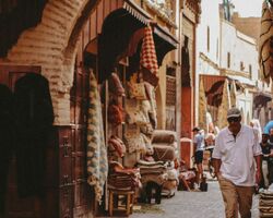 Ein Mann geht durch eine traditionelle Straße in der Medina von Marrakesch, Marokko, mit charakteristischer Architektur