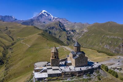 Hoch über Stepanzminda zählt die Gergetier Dreifaltigkeitskirche vor der Kulisse des 5.054 Meter hohen Kasbeks zu den berühmtesten Wahrzeichen Georgiens