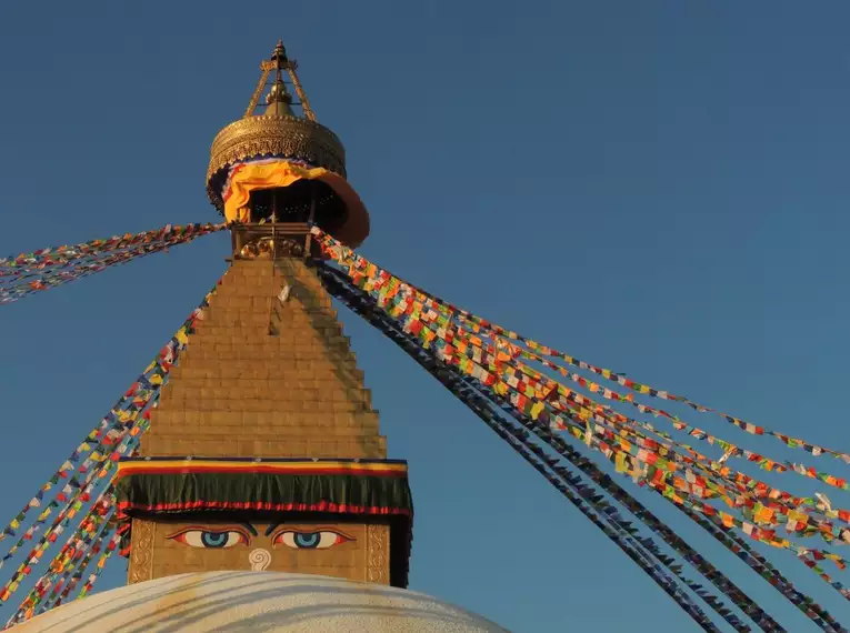 Detailansicht einer Stupa mit bunten Gebetsfahnen in Nepal bei klarem Himmel.