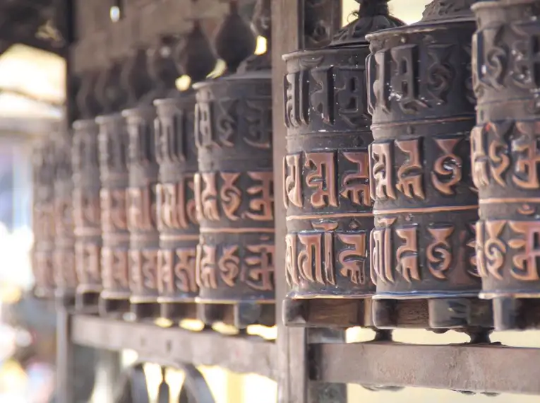 Reihe von Gebetsmühlen mit tibetischen Schriftzeichen in Nepal