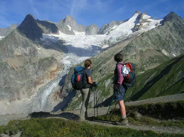 Zwei Wanderer stehen vor einem beeindruckenden Alpenpanorama im Mont Blanc Gebiet.