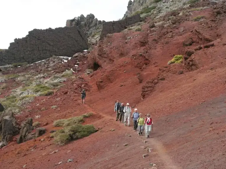 Wandergruppe auf einem roten Vulkanpfad auf La Palma, umgeben von einzigartigen Felsformationen und Landschaften.