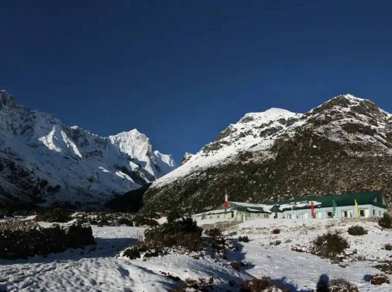 Panorama von schneebedeckten Bergen und einer grünen Lodge in Nepal.