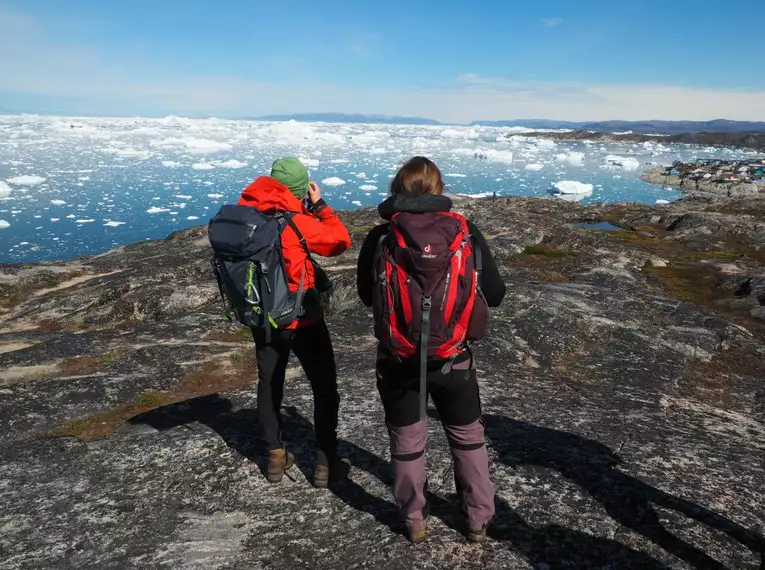 Unsere Wandergruppe hält Ausschau nach Robben Zwei Wanderer mit Rucksäcken betrachten Eisberge in Grönland.
