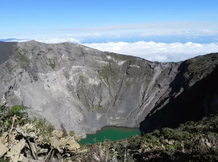 Blick in den Krater des Irazu Vulkans, umgeben von klarer Himmel und Vulkanlandschaft.