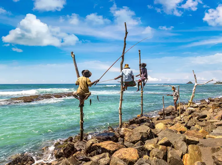 Fischer auf Stelzen am malerischen Strand von Sri Lanka