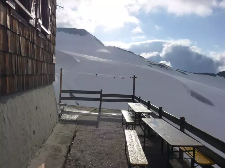 Holzhütte mit Aussicht auf schneebedeckte Berge in den Stubaier Alpen.