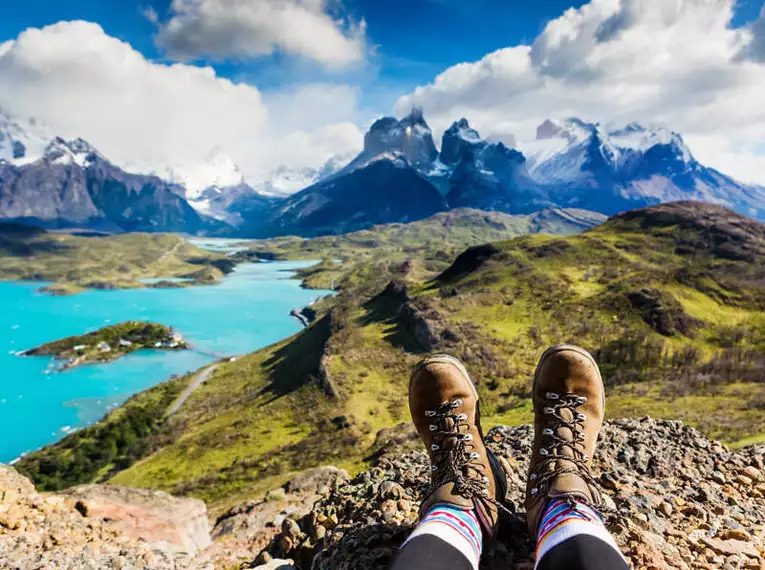Blick auf die Landschaft des Torres del Paine Nationalparks in Patagonien mit Wanderstiefeln im Vordergrund.