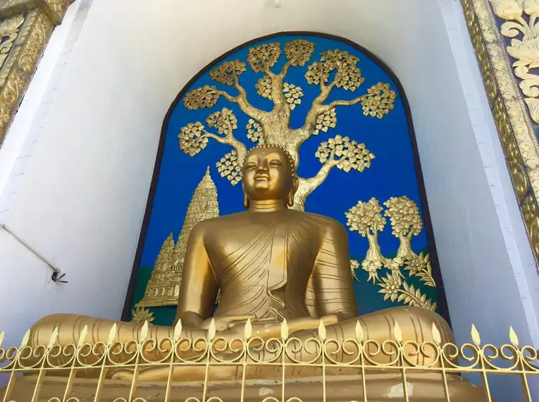 Goldene Buddha-Statue vor dekorativer Wand in Nepal.