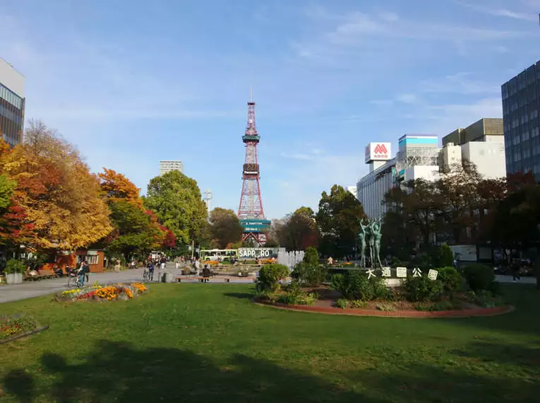 Sapporo TV Tower im Park Park in Sapporo mit grünen Rasenflächen und Sapporo TV Tower im Hintergrund.