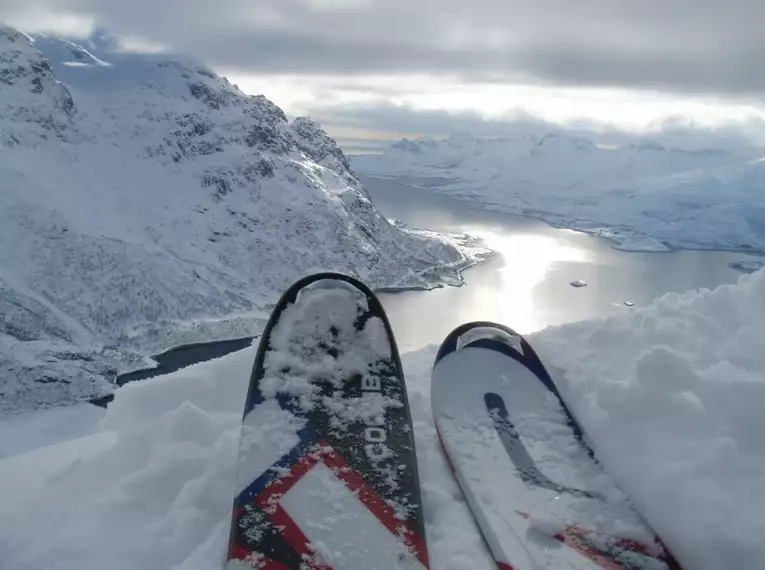 Ski & Meer - immer wieder toll auf den Lofoten Ski im Schnee mit Blick auf verschneite Berge und Fjord auf den Lofoten, Norwegen.