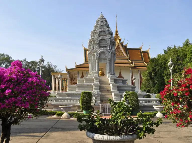 Eine beeindruckende weiße Tempelanlage umgeben von blühenden Bäumen in Phnom Penh.