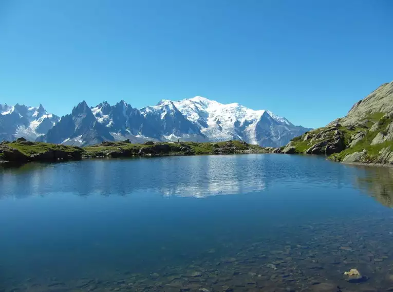 Klarer Bergsee mit schneebedeckten Gipfeln im Hintergrund, Mont Blanc Massiv.