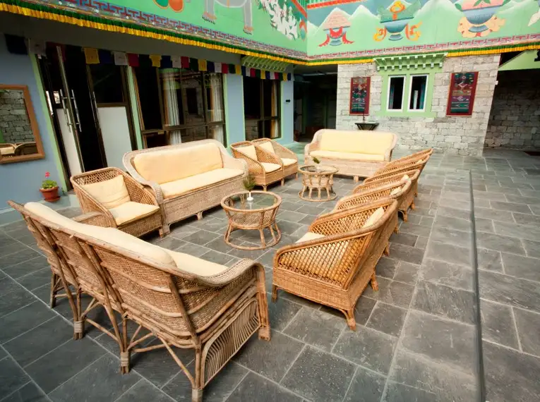 Rattanmöbel umgeben einen Tisch in einem Innenhof mit bemalten Wänden in einer Lodge.