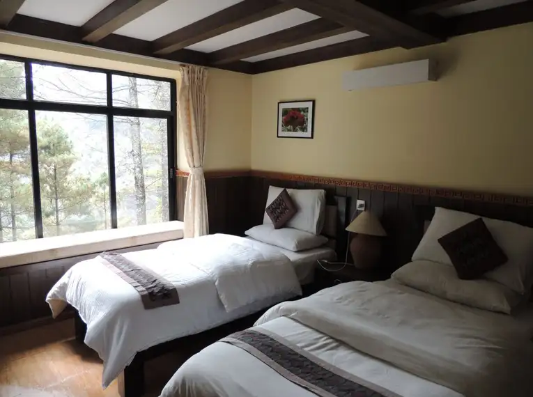 Zimmer mit zwei Betten und großem Fenster in einer Lodge im Himalaya