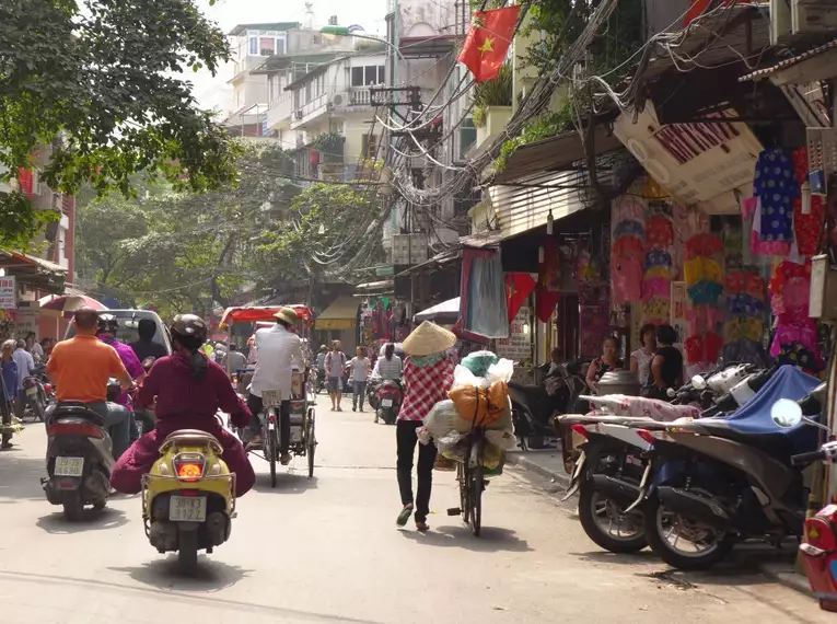 Straßenszene in Hanoi, Vietnam Menschen auf Fahrrädern und Mopeds in einer belebten Straße in Hanoi, Vietnam.
