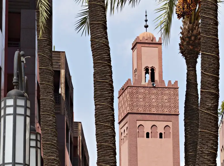 Marrakech Tour – Koutoubia-Moschee Koutoubia-Moschee in Marrakech, umgeben von Palmen, mit einem klaren Himmel im Hintergrund.