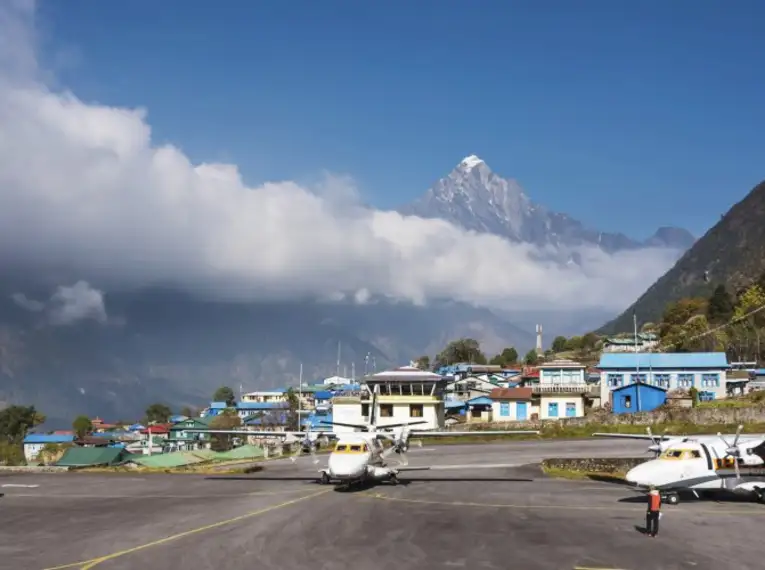 Flugzeuge am Flughafen Lukla, umgeben von Bergen und bewölktem Himmel in Nepal.