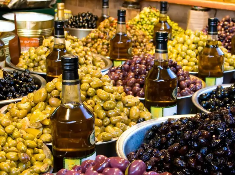 Griechischer Olivenmarkt Verschiedene Olivensorten und Olivenölflaschen auf einem Markt
