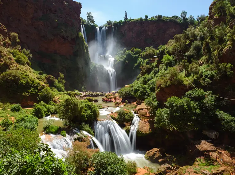 Die beeindruckenden Ouzoud-Wasserfälle umgeben von grüner Vegetation und klaren Wasserströmen in Marokko.