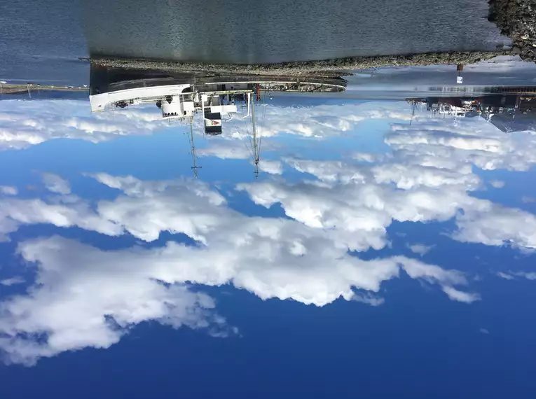 Zwei verankerte Schiffe unter blauem Himmel in einer ruhigen Hafenlandschaft.
