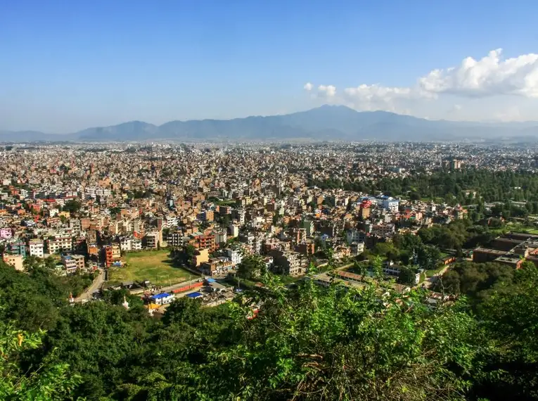 Panorama von Kathmandu mit umliegenden Hügeln unter blauem Himmel.