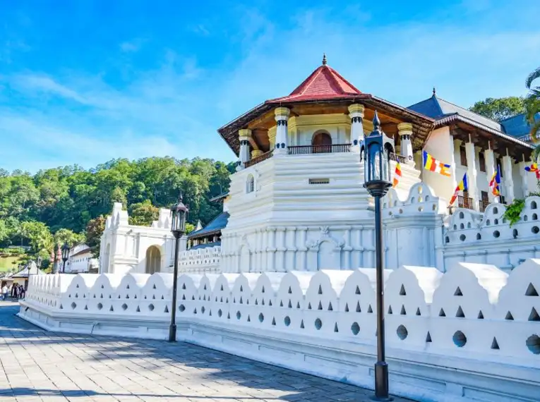 Der beeindruckende Tempel des Zahns in Kandy, umgeben von grüner Natur und strahlend blauem Himmel.